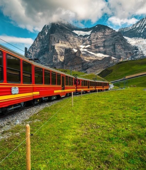 Mountain cogwheel railway with popular electric red tourist train. Jungfrau mountain with admirable glaciers and red passenger train, Jungfraujoch,  Grindelwald, Bernese Oberland, Switzerland, Europe